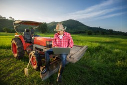 Farmer sitting on tractor using laptop
