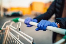 woman wearing gloves pushing shopping cart