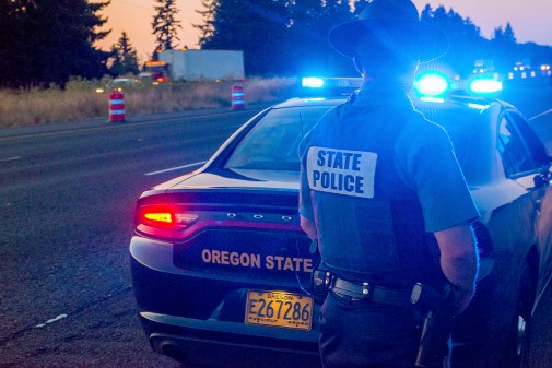 oregon state police officer standing by vehicle