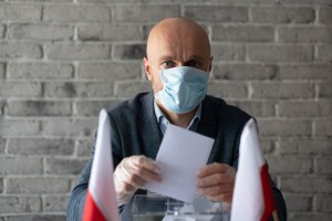 Man in medical mask putting his vote to voting ballot box