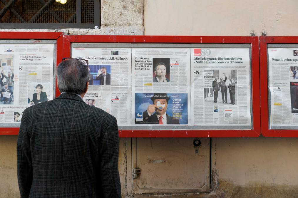 man looking at newsstand