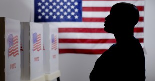Silhouetted figure by flag, voting booth