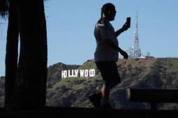 man looking at smartphone near Hollywood sign