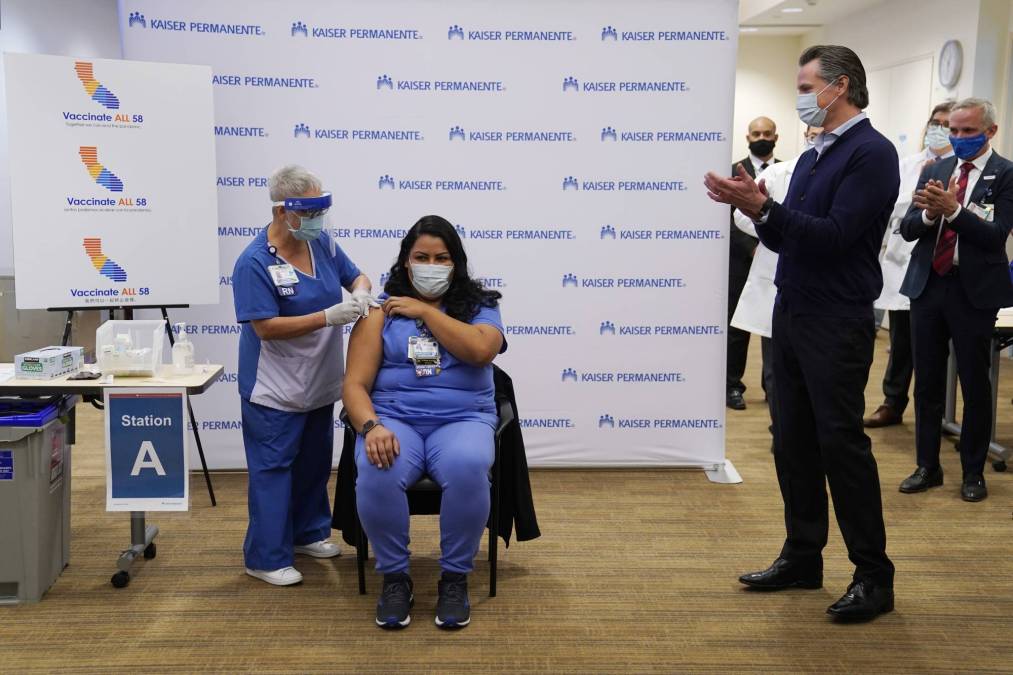 Gov. Gavin Newsom watches as ICU nurse Helen Cordova receives the Pfizer-BioNTech COVID-19 vaccine
