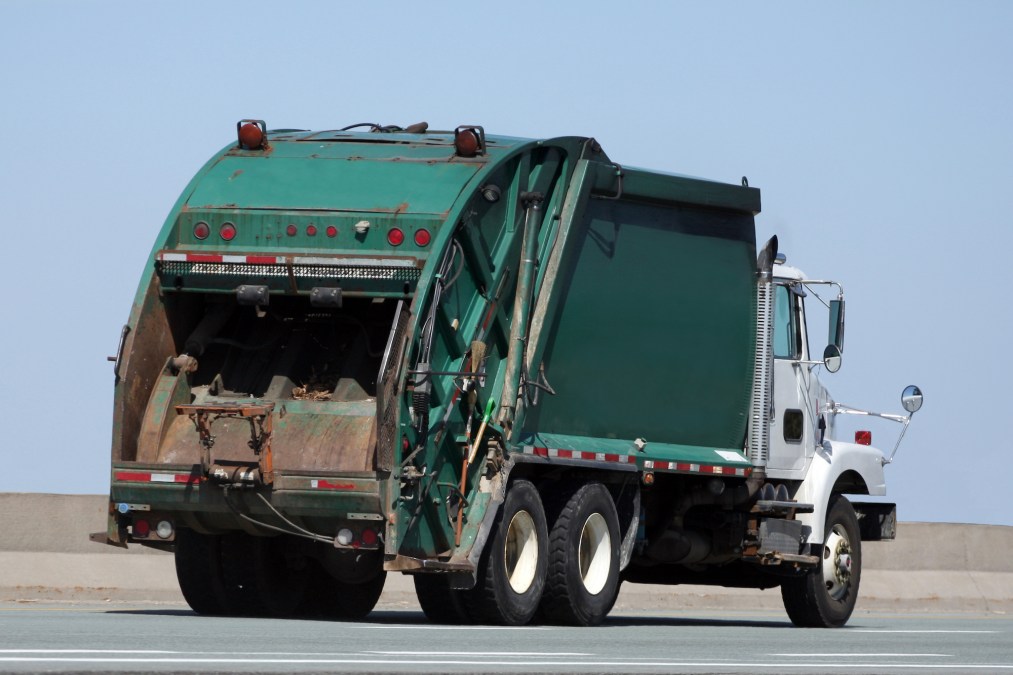 A garbage truck driving along an open road