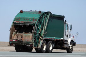 A garbage truck driving along an open road