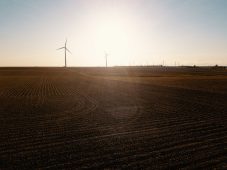 An aerial view of wind turbines in a farm field taken with a drone.