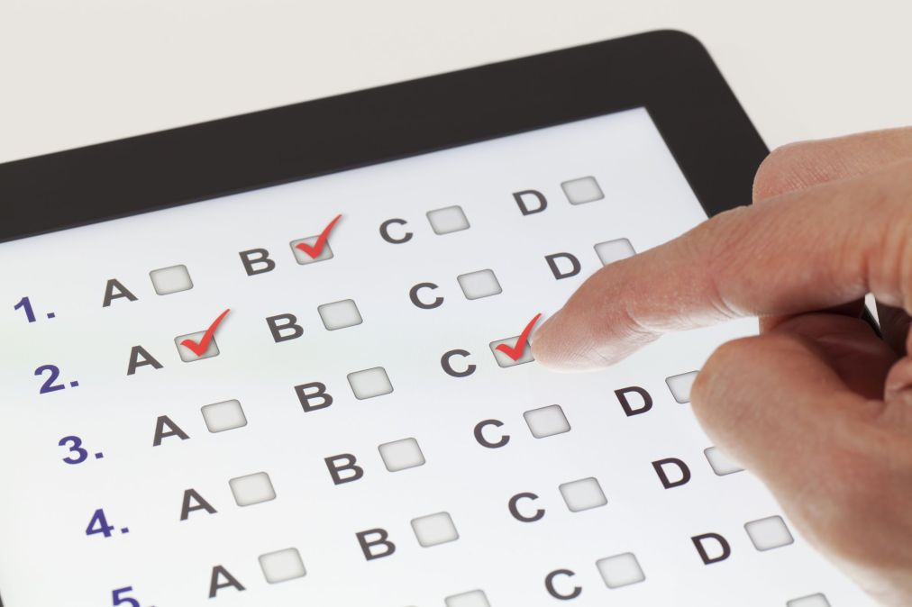 hand marking multiple choice answers on tablet
