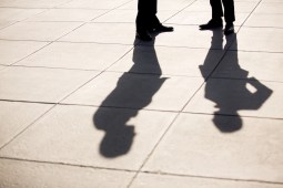 Long shadows of human figures on pavement