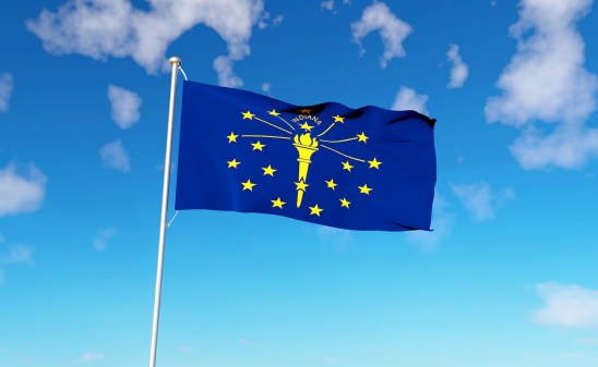 Indiana state flag on a blue sky background.