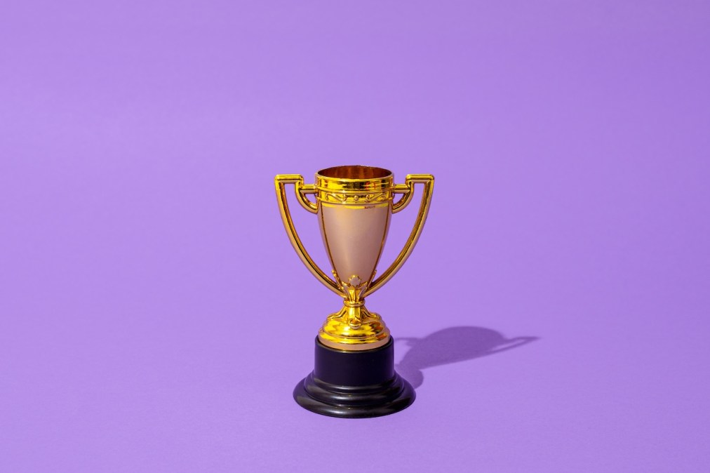 Close up of winner champion gold cup trophy on purple background. Harsh light. Concept of winner, victory, champion, world champion, sport.