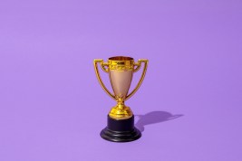 Close up of winner champion gold cup trophy on purple background. Harsh light. Concept of winner, victory, champion, world champion, sport.