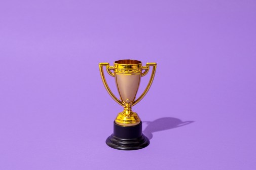 Close up of winner champion gold cup trophy on purple background. Harsh light. Concept of winner, victory, champion, world champion, sport.